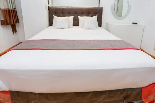 a bed with white sheets and pillows in a room at Super OYO Capital O Deroyal Sentra Timur in Jakarta