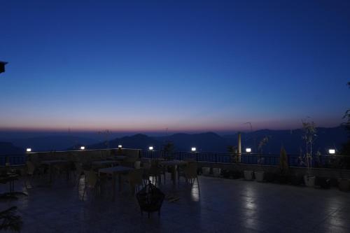 a patio with tables and chairs at night at The Uptown Kingdom Luxury Homestay in Mukteswar