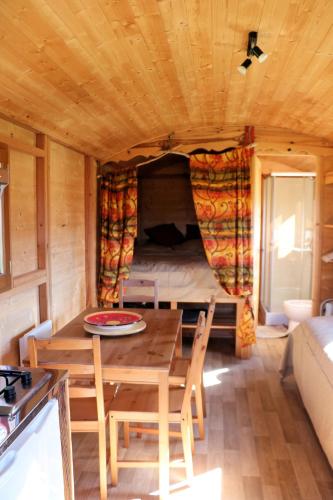 - une salle à manger avec une table et un lit dans une petite maison dans l'établissement Le nid des crinières vagabondes, à Oletta