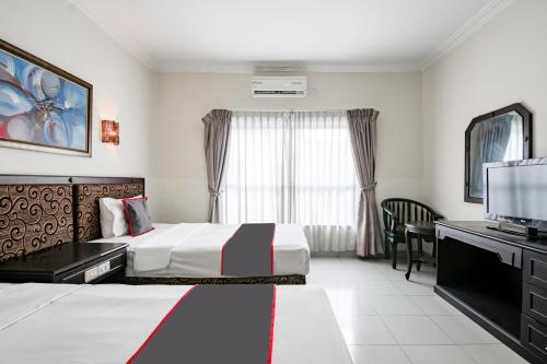 a hotel room with two beds and a flat screen tv at Collection O Senapelan Near Rsud Petala Bumi Formerly De Town Hotel in Pekanbaru