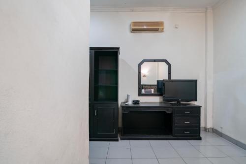 a black dresser with a mirror and a television at Collection O Senapelan Near Rsud Petala Bumi Formerly De Town Hotel in Pekanbaru