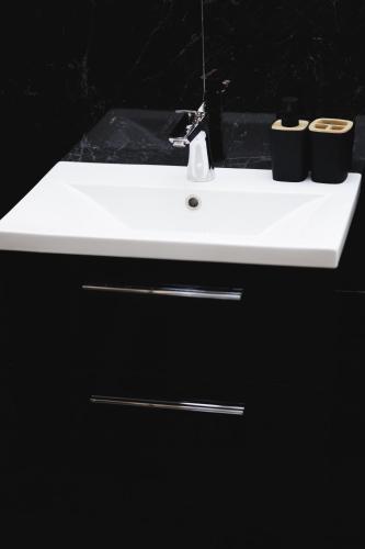 a white bathroom sink with two cups on it at Dom v stráni in Poniky