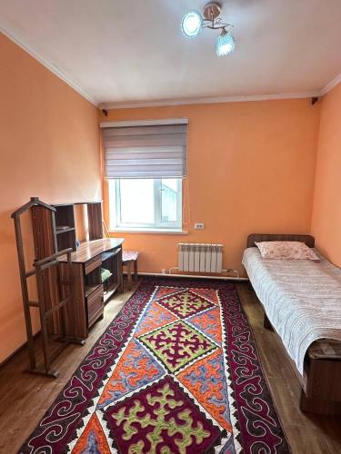 KochkorkaにあるTumar guest house, Kochkorのベッドルーム1室(ベッド1台、ラグ、デスク付)