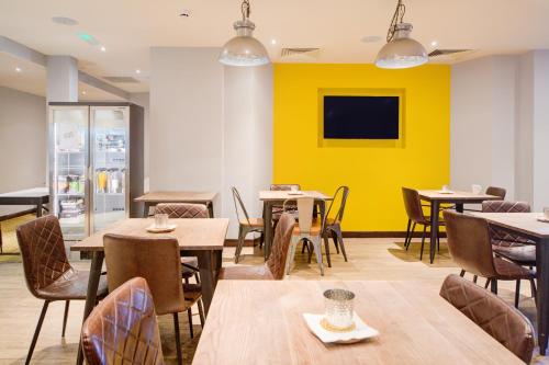 a restaurant with tables and chairs and a yellow wall at Belvilla Newport City Centre Lifestyle in Newport