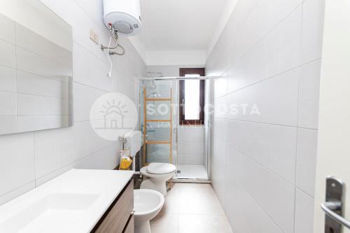 a white bathroom with a toilet and a sink at Alice Flat - SAN FOCA in San Foca