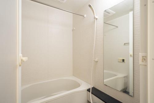 a white bathroom with a tub and a mirror at Granado Roppongi in Tokyo