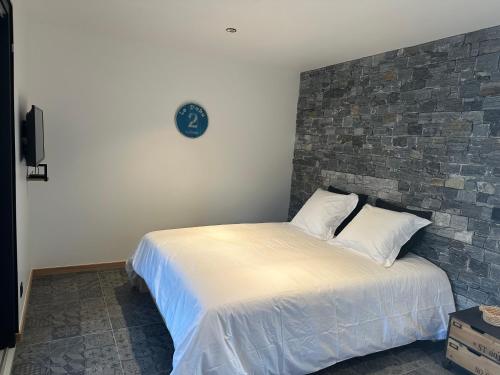 a bed in a bedroom with a brick wall at Les Tchanquées in Bourg-Fidèle