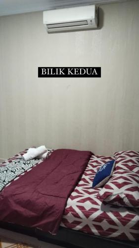 a bed in a room with a sign on the wall at Odah Homestay in Bedung