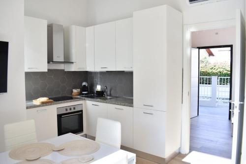 a kitchen with white cabinets and a table and chairs at Renovated villa 400 meters from the sea with garden in Forte dei Marmi
