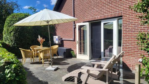 a patio with a table and chairs and an umbrella at Prachtige Vakantiewoning 'la bienvenue' in Venlo, Limburg in Venlo