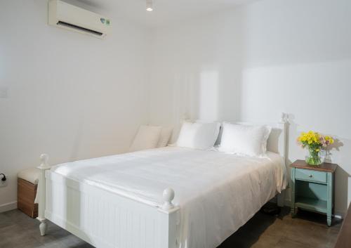 a white bed with white sheets and pillows at Rennoki Homestay - A Green Oasis in HCMc in Ho Chi Minh City