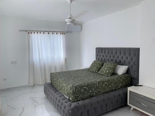 a bedroom with a bed with green sheets and a ceiling at Villa Muñoz in San Felipe de Puerto Plata