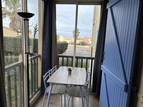 une table et des chaises sur un balcon avec une fenêtre dans l'établissement SP570-302 Studio cabine loggia ST PIERRE LA MER, à Saint Pierre La Mer