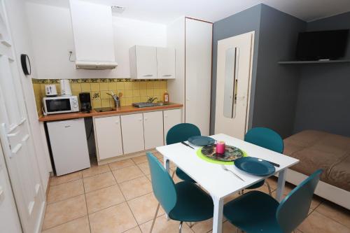 une cuisine et une salle à manger avec une table et des chaises blanches dans l'établissement Grande studio 2 coeur des animations à 50m plage, à Argelès-sur-Mer