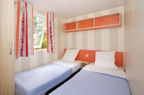 滨海阿热莱斯Camping maeva Escapades Les Abricotiers的一间带窗户的小房间里有两张床