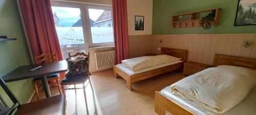 a bedroom with two beds and a desk and a window at Backerwirt - Wohnen und Schlafen in Welden