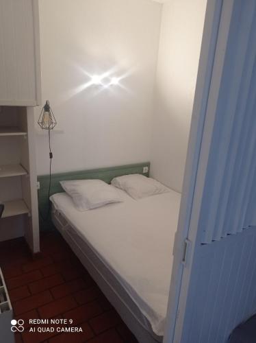 une chambre avec un lit avec une lumière sur le mur dans l'établissement Petit cocon avec terrasse à 150m de l'océan, à Soulac-sur-Mer