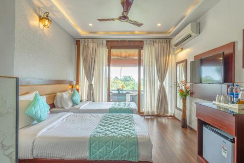 a hotel room with two beds and a television at Salcete Beach Resort in Colva
