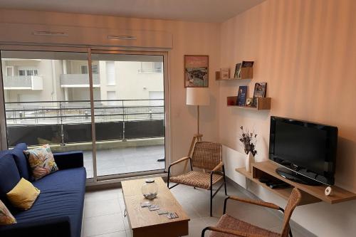 un salon avec un canapé bleu et une télévision dans l'établissement Cozy T2 with balcony near the sea, à Saint-Malo