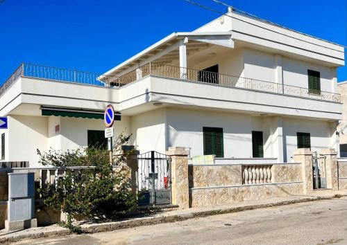 a white house with a balcony on a street at The Front Beach Penthouse 20 m by Salento Prime in Marina di Pescoluse