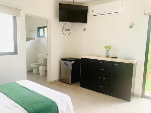 a bedroom with a bed and a television on the wall at Quinta YaaxBe in Homún