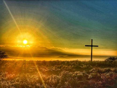 a cross in a field with the sunset in the background at Natures Rest Lapa in Oudtshoorn