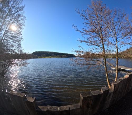 - une vue sur un grand lac avec des arbres sur la rive dans l'établissement L'Ancien Moulin du Château de Marrault - Gîte de groupe, à Magny