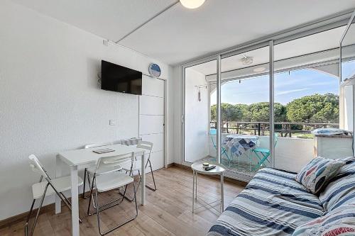 un salon avec un canapé et une table avec des chaises dans l'établissement Le Cordier - Apartment near the harbor, à Gruissan