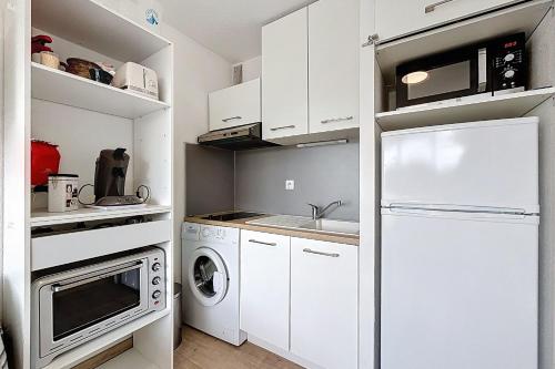 une cuisine avec des armoires blanches et un réfrigérateur blanc dans l'établissement Le Cordier - Apartment near the harbor, à Gruissan