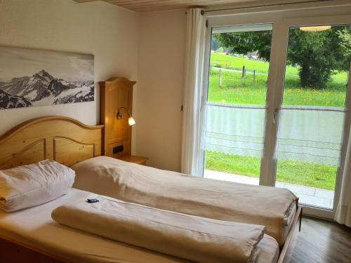 a bedroom with two beds and a large window at Ferienhof "Alpe Berg" in Balderschwang