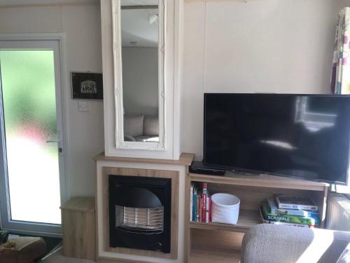 a living room with a television and a fireplace at Badgers nestled in a cozy corner of the park in Wadebridge