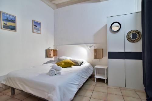 - une chambre avec un lit blanc et une horloge murale dans l'établissement L'Amuros - Wifi- 200m plage, à Saint-Malo