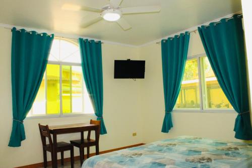 a bedroom with blue curtains and a table and a bed at Alona Austria Resort in Panglao