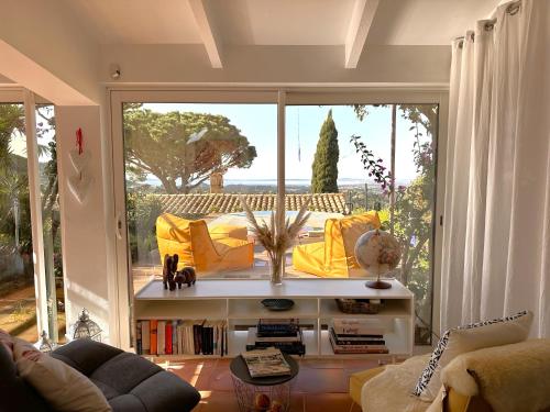 - un salon avec un canapé jaune et une grande fenêtre dans l'établissement Le Lavandin Maison pour 4 personnes avec piscine et vue panoramique à La Londe Les Maures, à La Londe-les-Maures