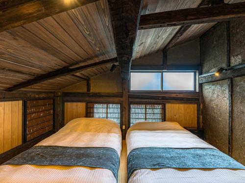 two beds in a room with a roof at NIPPONIA Sado 佐渡相川 金山町 in Sado