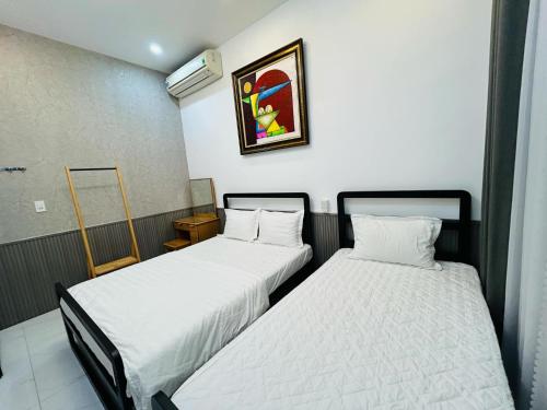 two beds in a hotel room with white sheets at MUN HOMESTAY in Hue