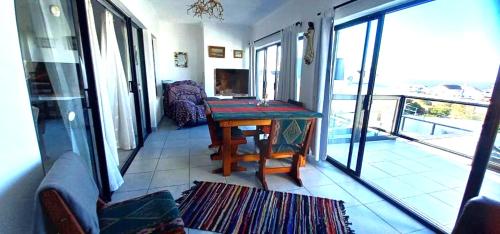 a living room with a table and a balcony at Columbine Views in Stompneusbaai