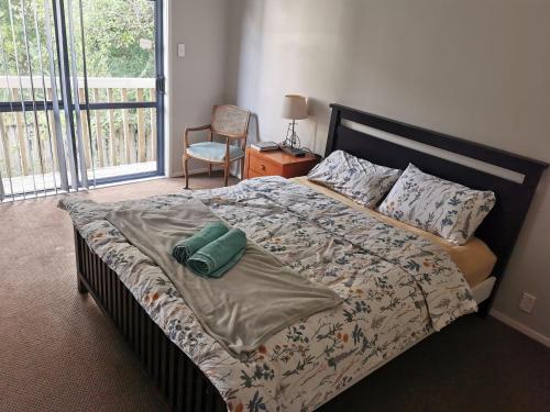 a bedroom with a bed and a chair and a window at LD Home in Auckland