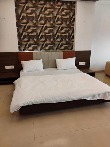 a bedroom with a large bed with white sheets at hotel nova haven in Ankleshwar