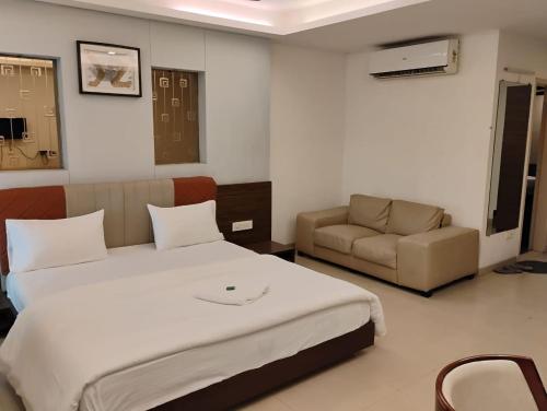 a bedroom with a large bed and a couch at hotel nova haven in Ankleshwar