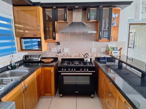a kitchen with a black stove and a sink at Modern Beachfront Unit with Breathtaking Seaview's in Mtwalume