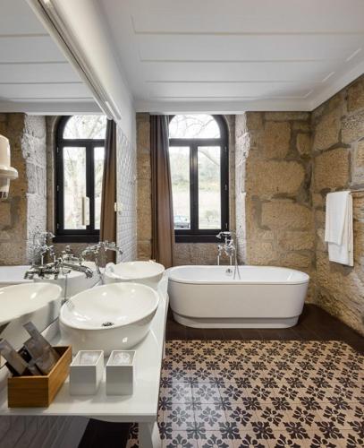 a large bathroom with two sinks and a tub at Longroiva Hotel Rural in Longroiva