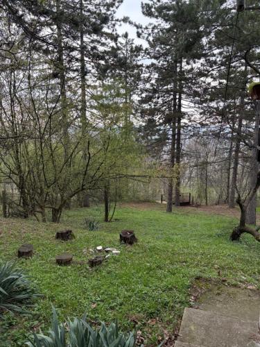 a park with trees and green grass and logs at Kuca u sumi Kosmaj in Sopot