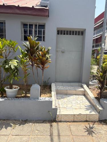 una casa bianca con una porta e alcune piante di Sipim aéroport a Abidjan