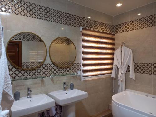 ein Badezimmer mit zwei Waschbecken und einer Badewanne und Spiegeln in der Unterkunft Zebra Résidence in Bambilor