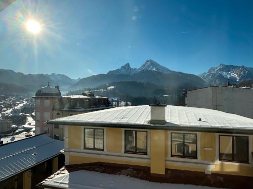 a building with a roof with mountains in the background at Alpine Apartements Maximilian in Berchtesgaden