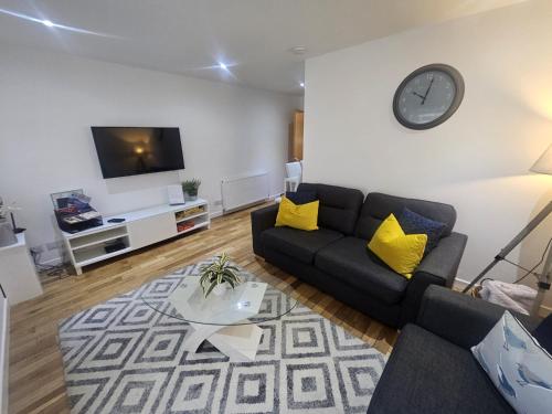a living room with a couch and a clock on the wall at LANGLEY APARTMENT free parking outside between 6 pm and 8 am Secure parking 2 min walk Ideal for TRADES AND TOURISTS WANTING GREAT LOCATION in Inverness
