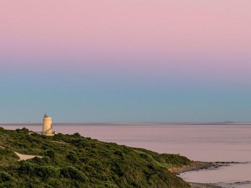 a lighthouse sitting on top of a hill next to the ocean at Fairmont La Hacienda Costa del Sol in Alcaidesa