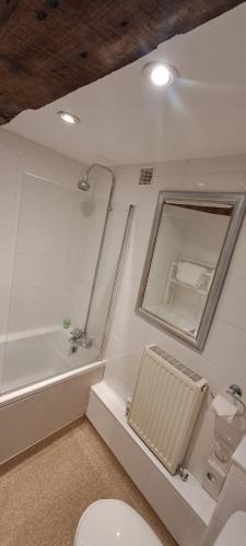 a bathroom with a tub and a toilet and a mirror at Earsham Street House in Bungay