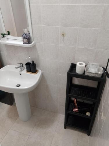 a bathroom with a sink and a toilet and a shelf with towels at La casa nella Valle in Monti di Licciana Nardi